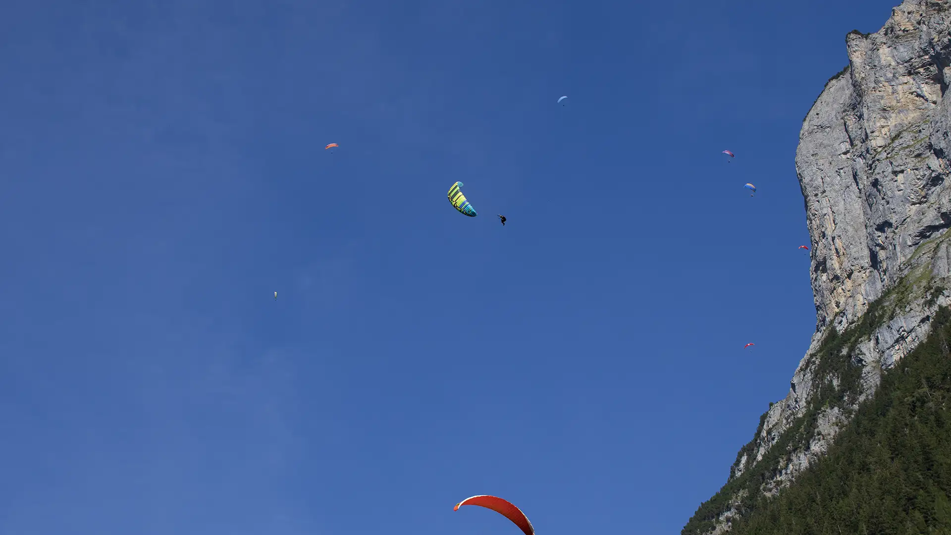 Several paragliders flying with one performing acrobatics